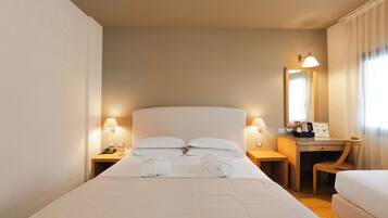 Une chambre d’hôtel avec un grand lit, un bureau avec une chaise, un miroir et deux lampes de chevet.