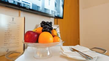A fruit bowl on a table with a menu to the left and a TV in the background.
