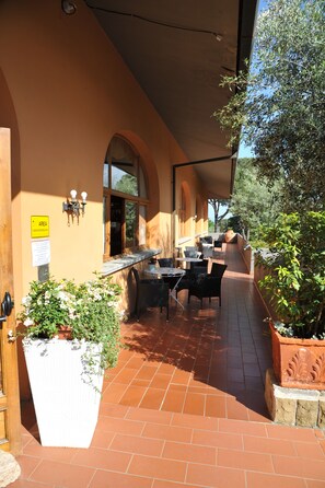 An outdoor patio area with a table and chairs, a potted plant, and a sign indicating an area. - Hotel Hermitage (Poggio a Caiano)