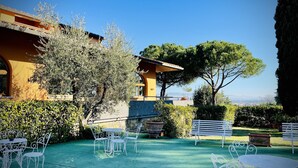Un cortile con posti a sedere all'aperto, un edificio con pareti gialle e vista sul paesaggio.