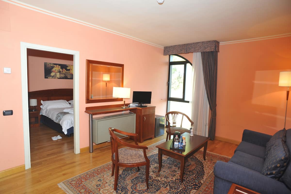A hotel room with a bed, desk, chair, and a sofa.