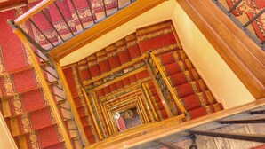 Una escalera de caracol con escalones alfombrados y barandillas de madera ornamentadas.
