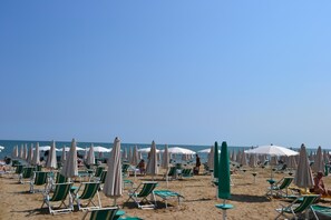 A beach with rows of green and white lounge chairs and umbrellas. - Hotel Stockholm (Jesolo)
