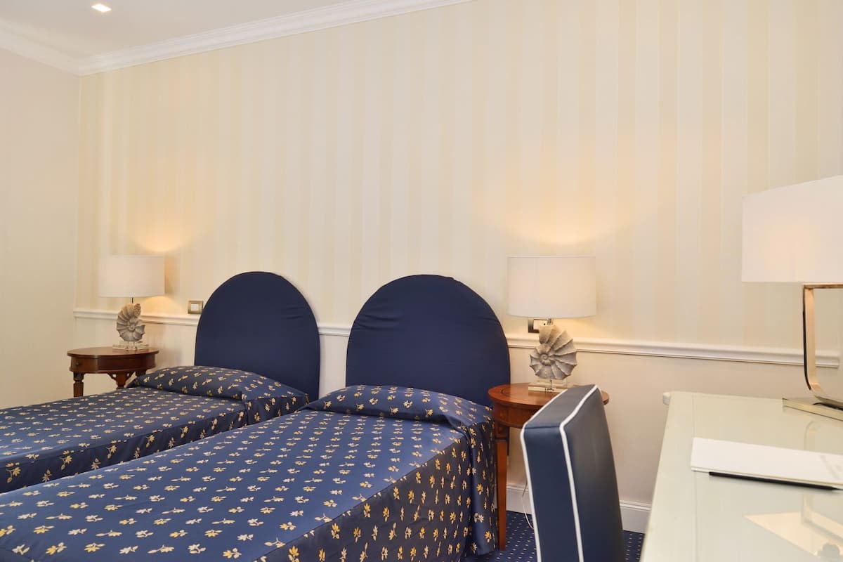 Een hotelkamer met twee bedden, een bureau en een stoel.