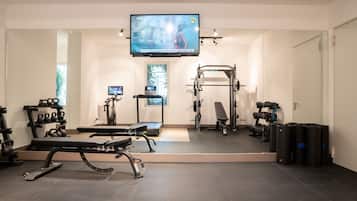 Una palestra moderna con attrezzature per esercizi, uno schermo televisivo e un grande specchio.