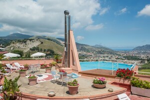 En tagterrasse med swimmingpool, liggestole og plantekasser.