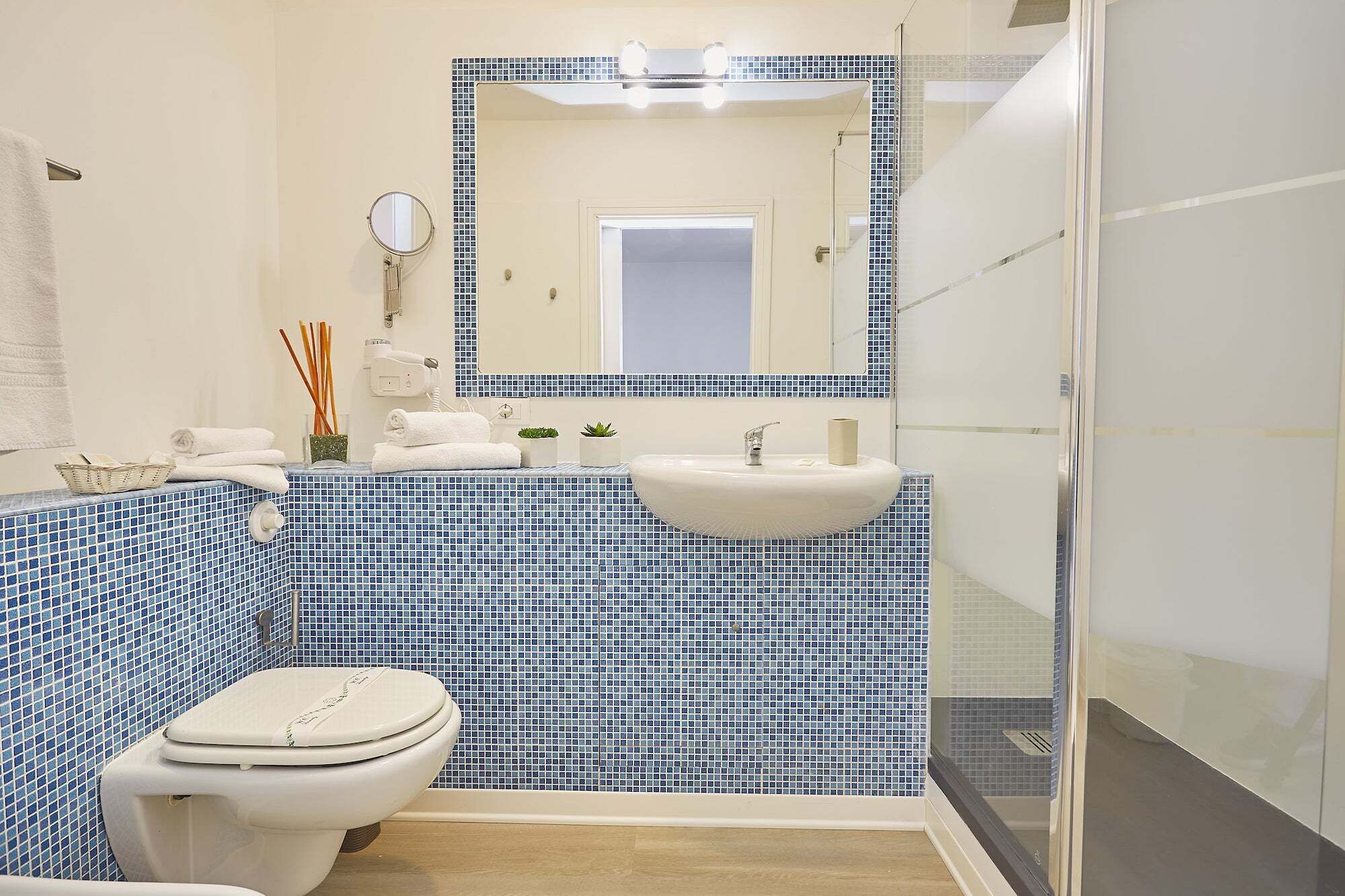 A bathroom with a toilet, sink, and mirror.