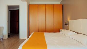 A hotel room with a bed, a wooden wardrobe, a nightstand, and a lamp.
