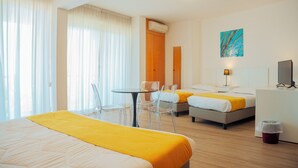 A hotel room with a bed, a desk, a chair, a small table, a TV, and a painting on the wall.