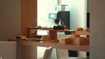 A modern dining area with a wooden counter, white chairs, and pendant lighting.