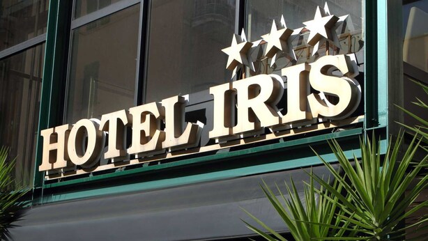 Placa de hotel com o nome 'HOTEL IRIS' e estrelas decorativas acima do texto.