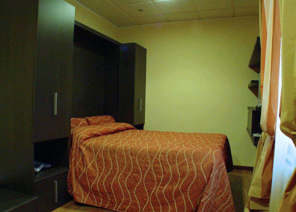A hotel room with a bed, a wardrobe, and a television.