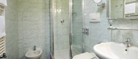 A bathroom with a glass-enclosed shower, a bidet, a toilet, and a sink.