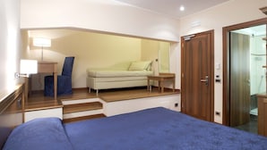 Quarto com cama, sofá, mesa de cabeceira, luminária e porta para um banheiro.