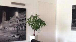 A modern living room with a black leather sofa, a coffee table, and a potted plant. - Hotel Al Cason (Padova)