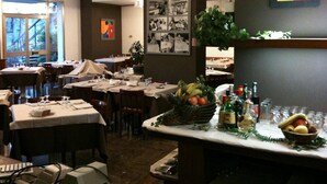 A restaurant with tables set for dining, a bar area with bottles and glasses, and a wall with black and white photos. - Hotel Al Cason (Padova)