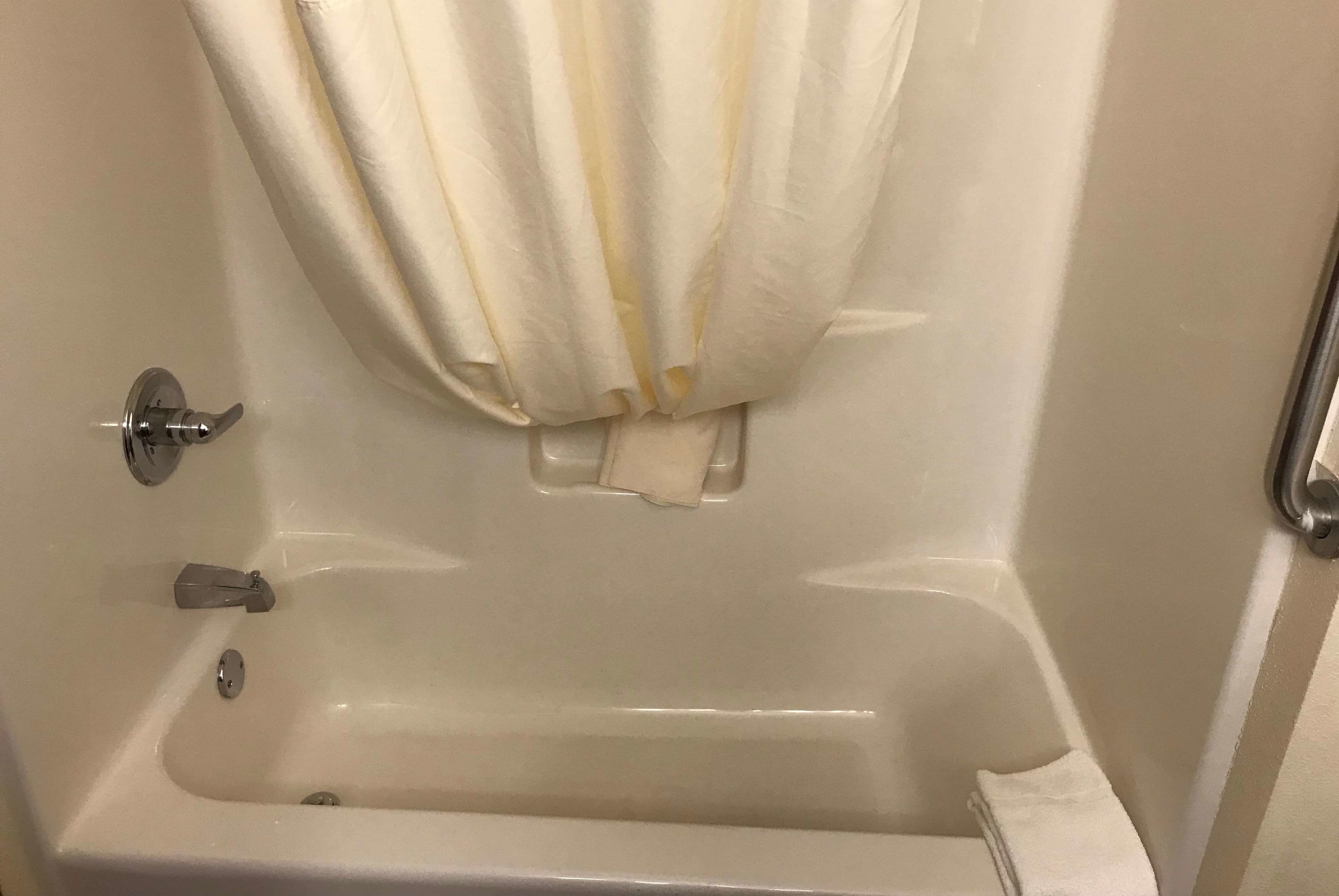 Une baignoire avec un rideau de douche, un robinet et une serviette.