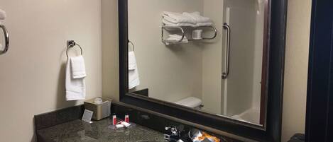 A bathroom with a sink, mirror, towel rack, and toiletries.