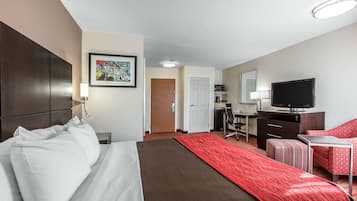 Ein Hotelzimmer mit einem Bett, einem Schreibtisch, einem Fernseher und einem roten Teppich.