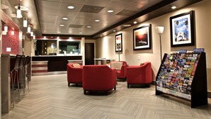 Vestíbulo de hotel con mostrador de recepción, zona de estar roja y un expositor con folletos.