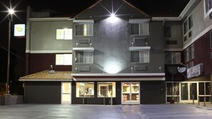 Un edificio de varios pisos con techo plano, ventanas grandes y una entrada visible con puertas de vidrio.