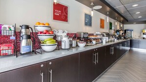 Una barra de desayuno con diversas opciones de alimentos, una cafetera y una tetera.