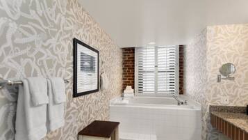 A bathroom with patterned wallpaper, a bathtub, a sink, and a mirror.