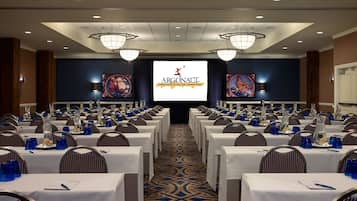A conference room with rows of tables, chairs, and a large screen displaying the Argonaut logo.