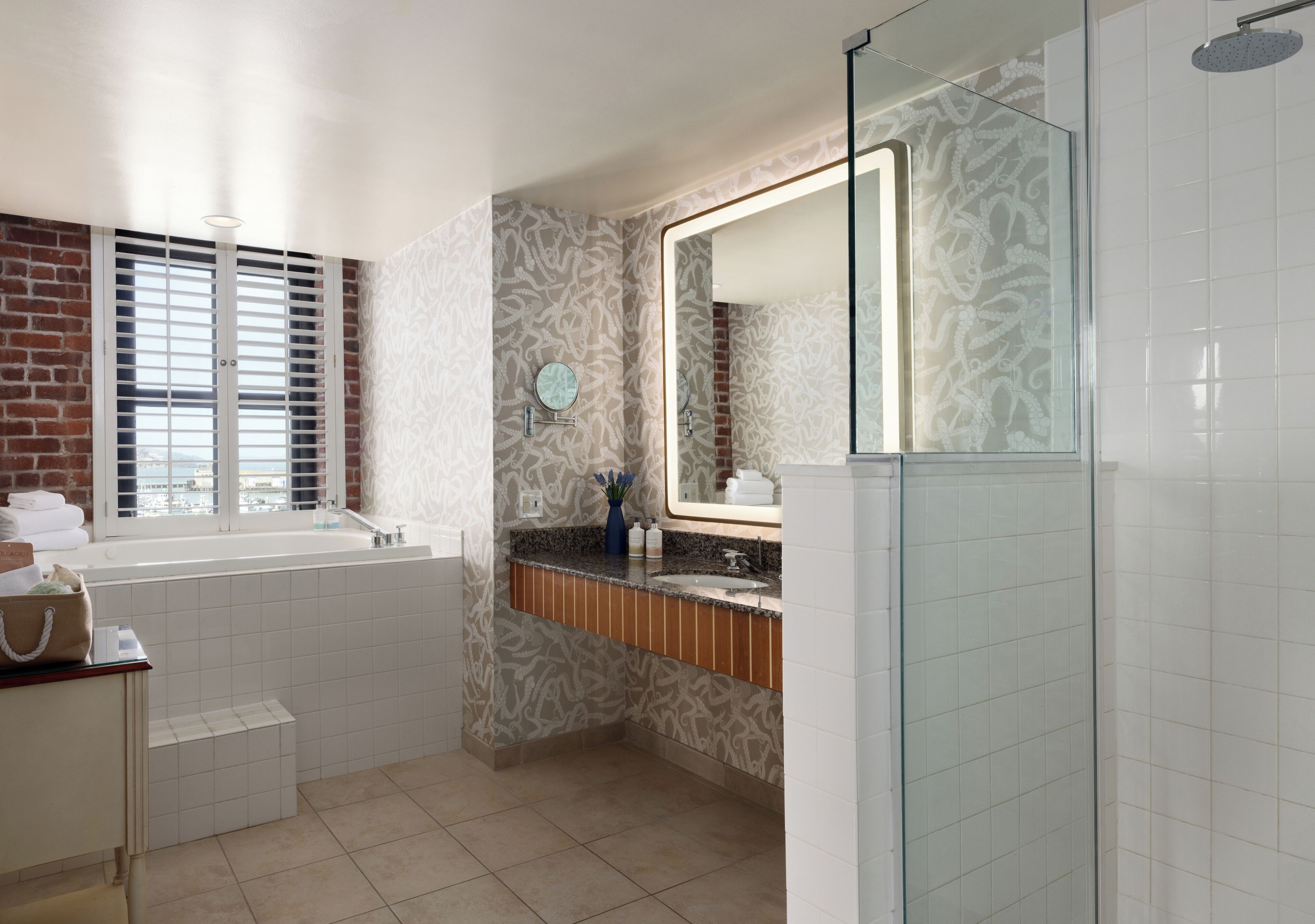 Ein Badezimmer mit einer Badewanne, einer Duschkabine aus Glas, einem Waschtisch mit Spiegel und fugenwerkgelegtem Boden.