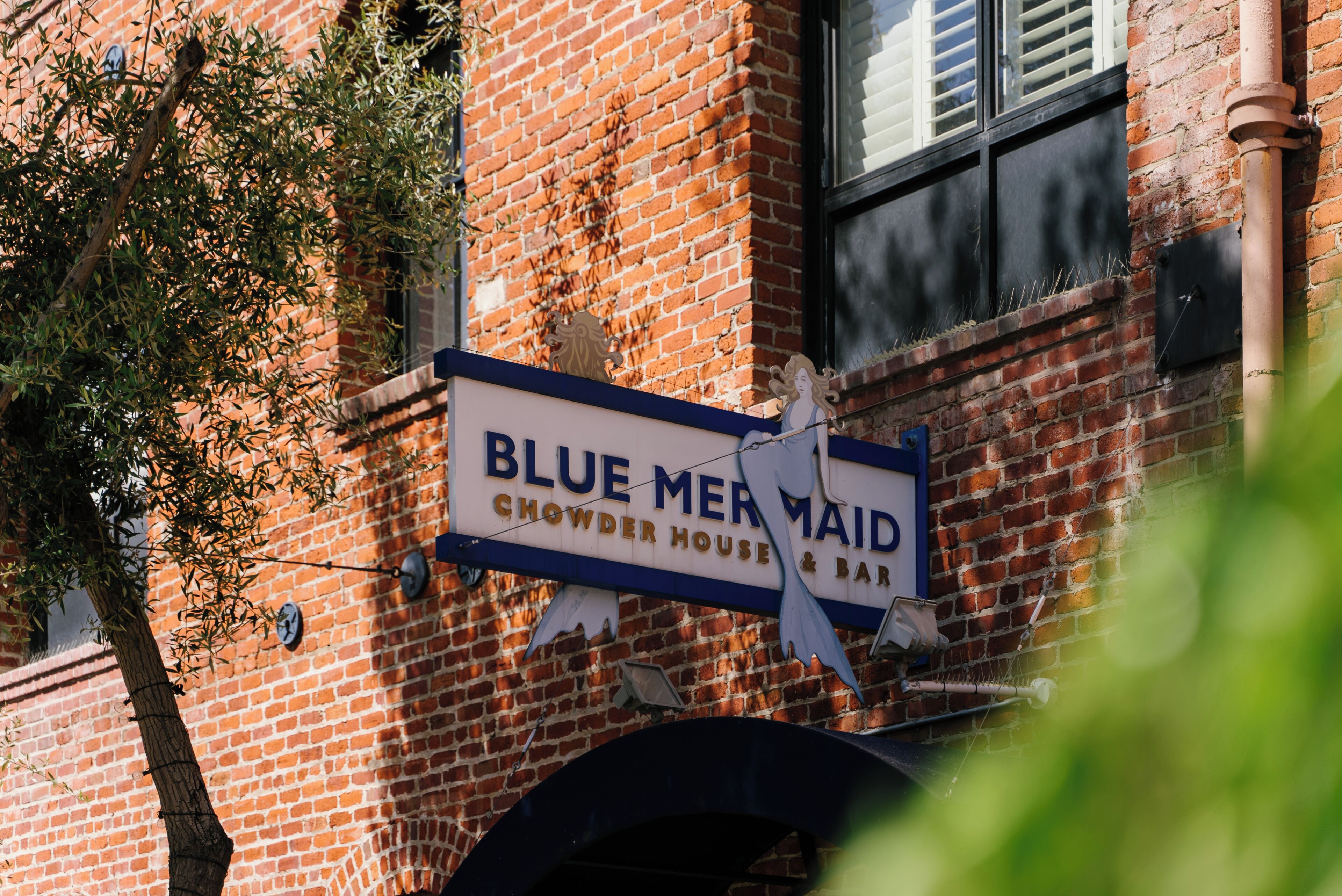 Naamplaatje voor 'Blue Mermaid Chowder House & Bar' op een bakstenen gebouw.