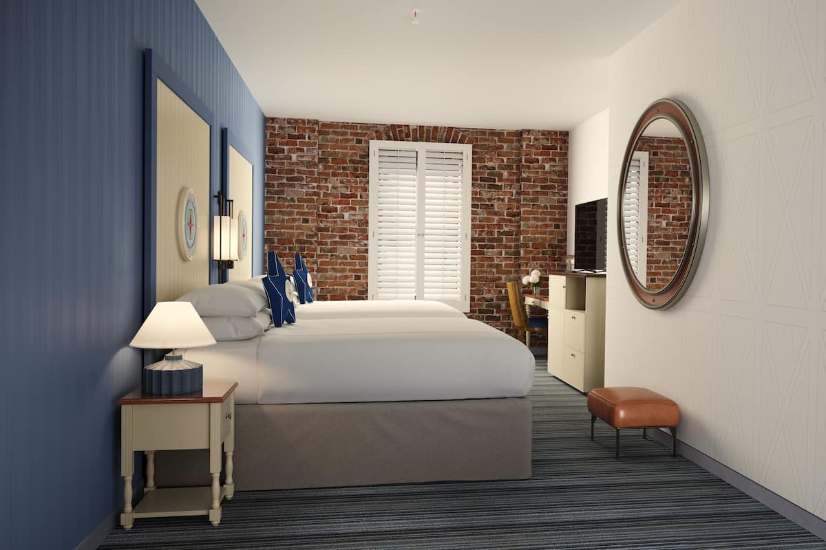 Een hotelkamer met een bed, nachtkastje, bureau, stoel en grote spiegel.