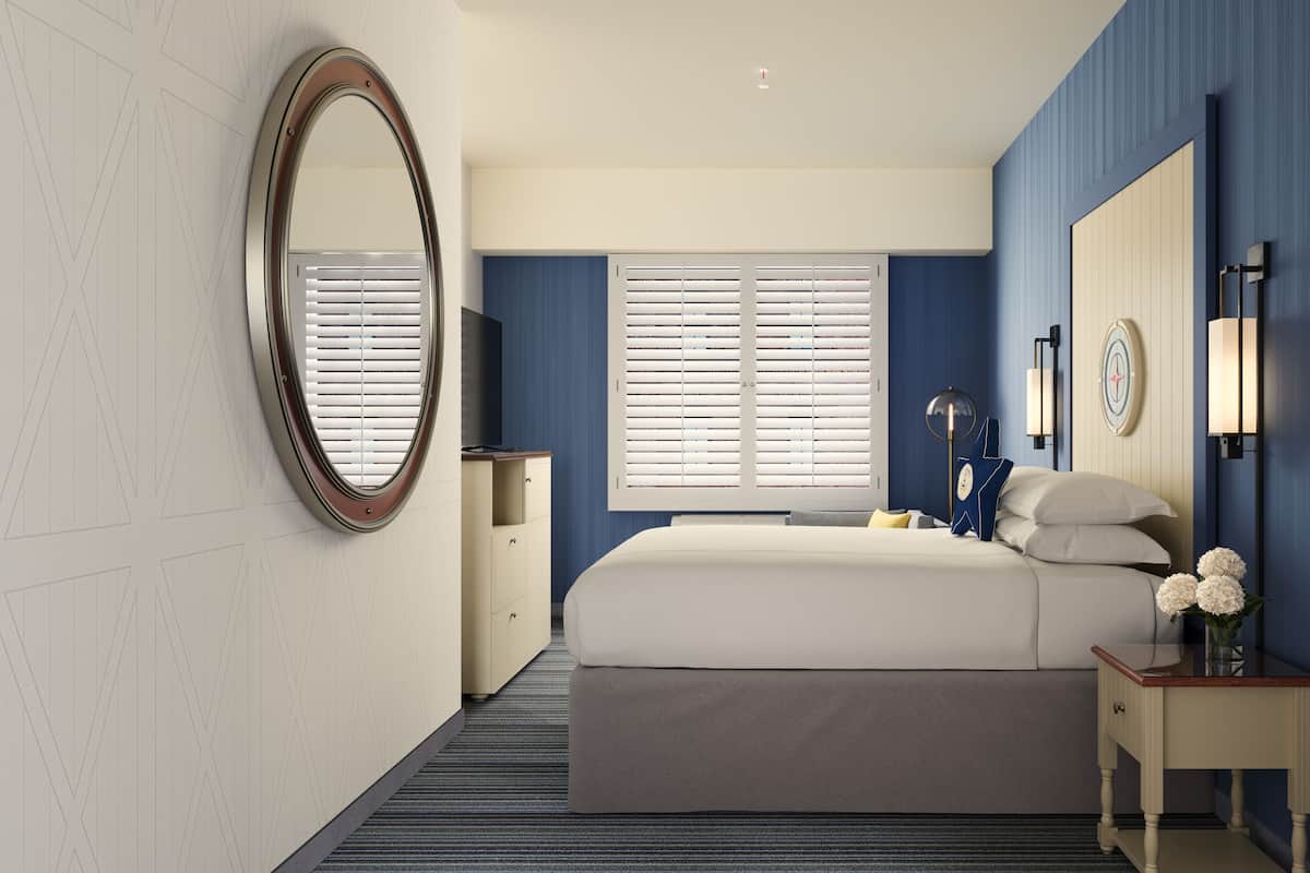 Een slaapkamer met een groot bed, een nachtkastje, een spiegel en een raam met jaloezieën.