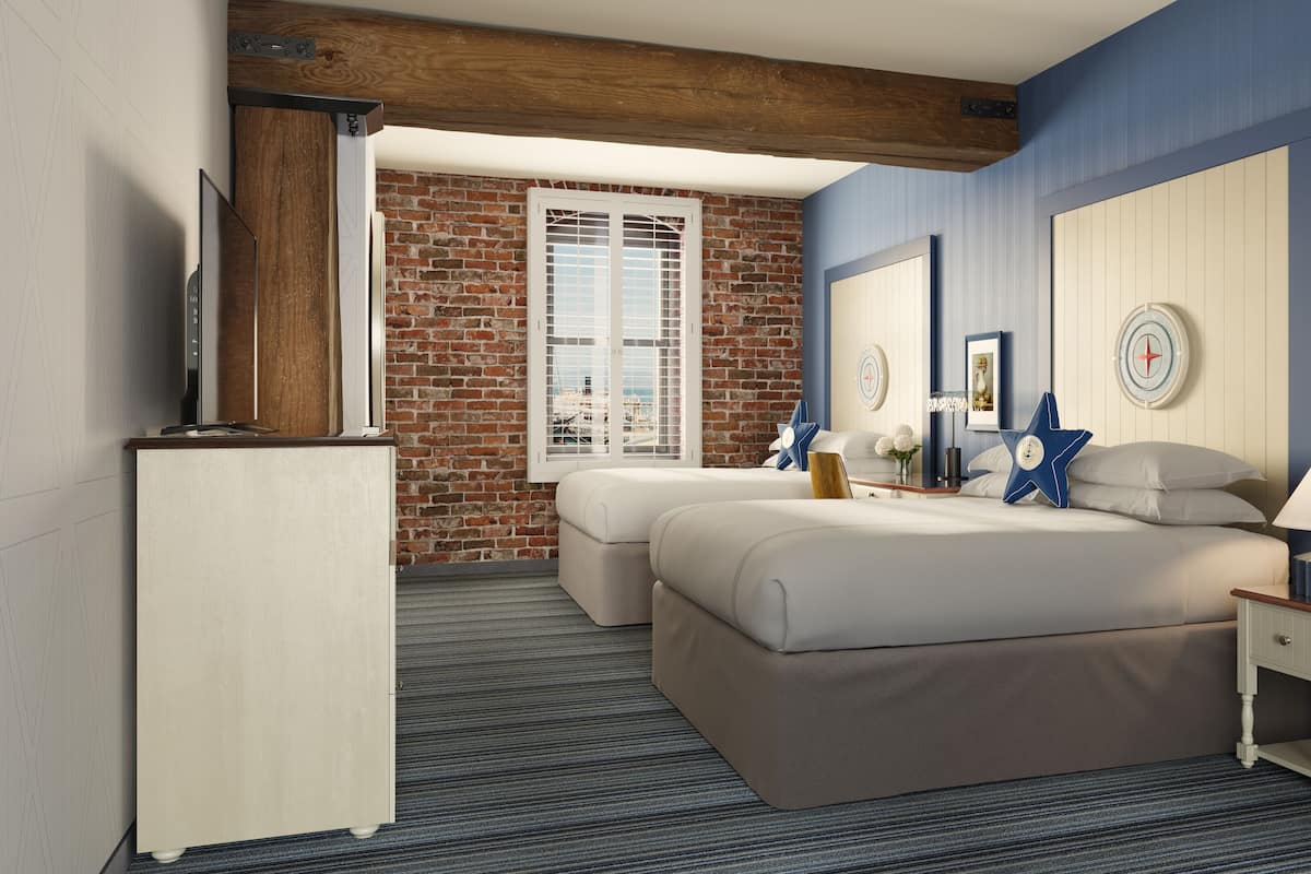Een hotelkamer met een bakstenen muur, een groot bed, een televisie en een nachtkastje met een lamp.