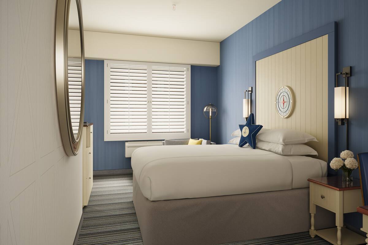 Een hotelkamer met een groot bed, een nachtkastje met een lamp, een stoel en een raam met jaloezieën.