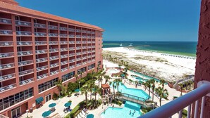 Un hotel con varios balcones, una zona de piscina y vista al mar.