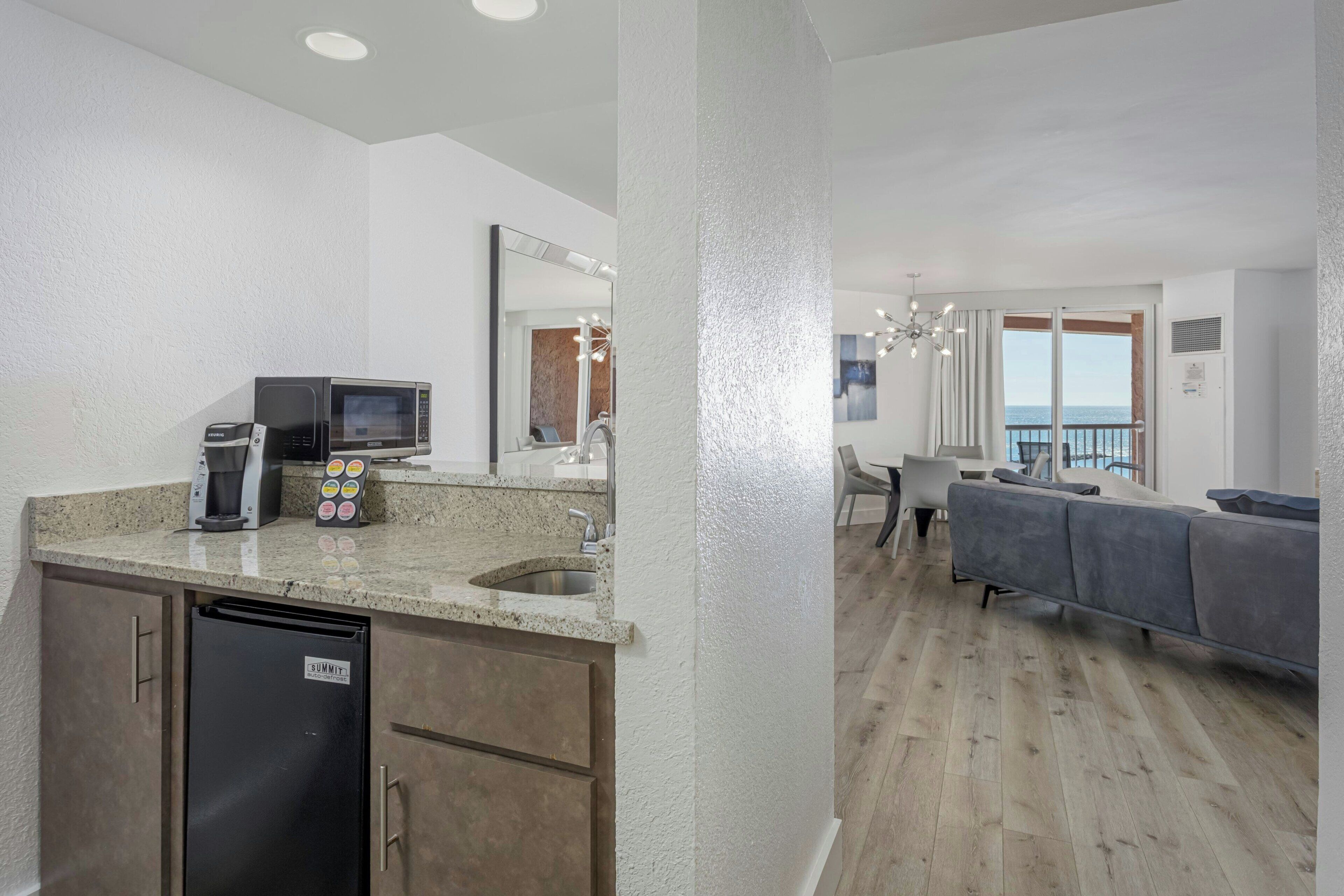 A modern kitchen with a built-in microwave, coffee maker, and a refrigerator.