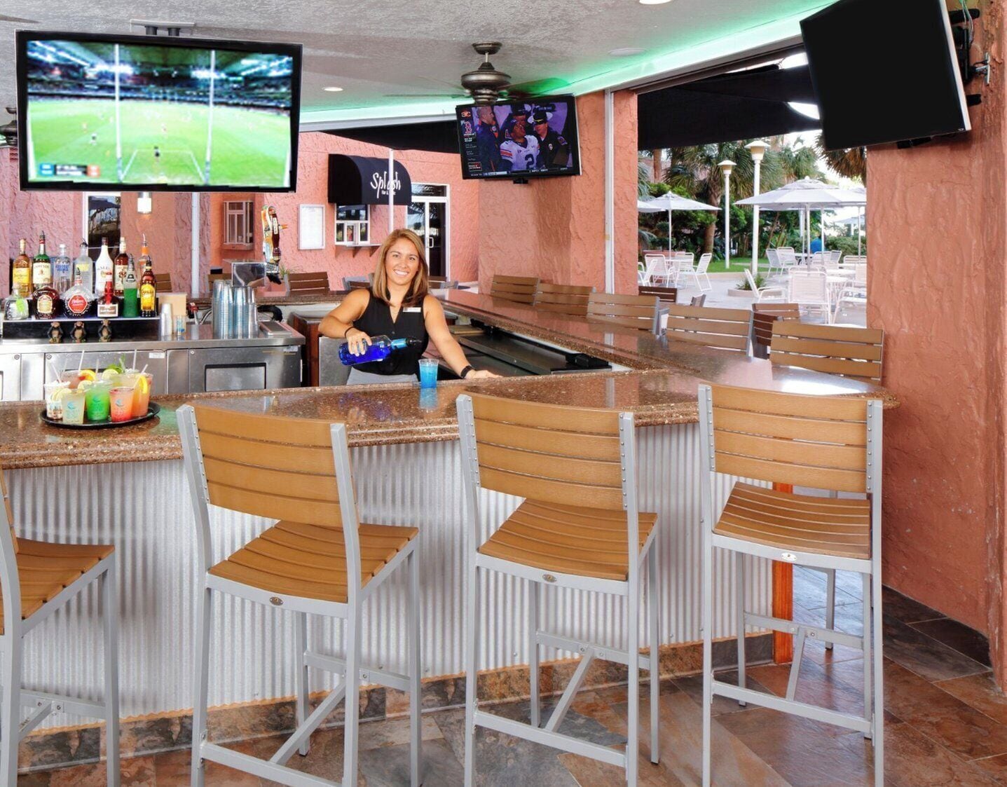 Eine Bar mit einer Theke, Stühlen und einem Fernsehbildschirm, der ein Sportevent zeigt.