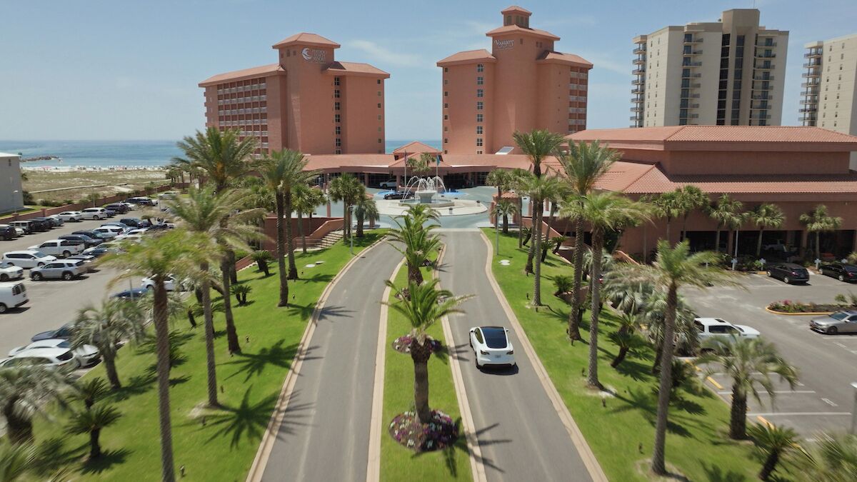 A hotel with a central courtyard, palm trees, and a parking lot.