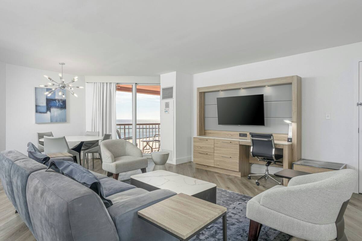 A modern living room with a sofa, coffee table, TV, and a balcony view.