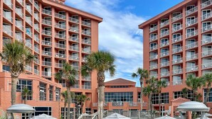 Un hotel con varias plantas, piscinas exteriores y palmeras.
