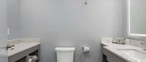 Ein Badezimmer mit Toilette, zwei Waschbecken und einem Spiegel.
