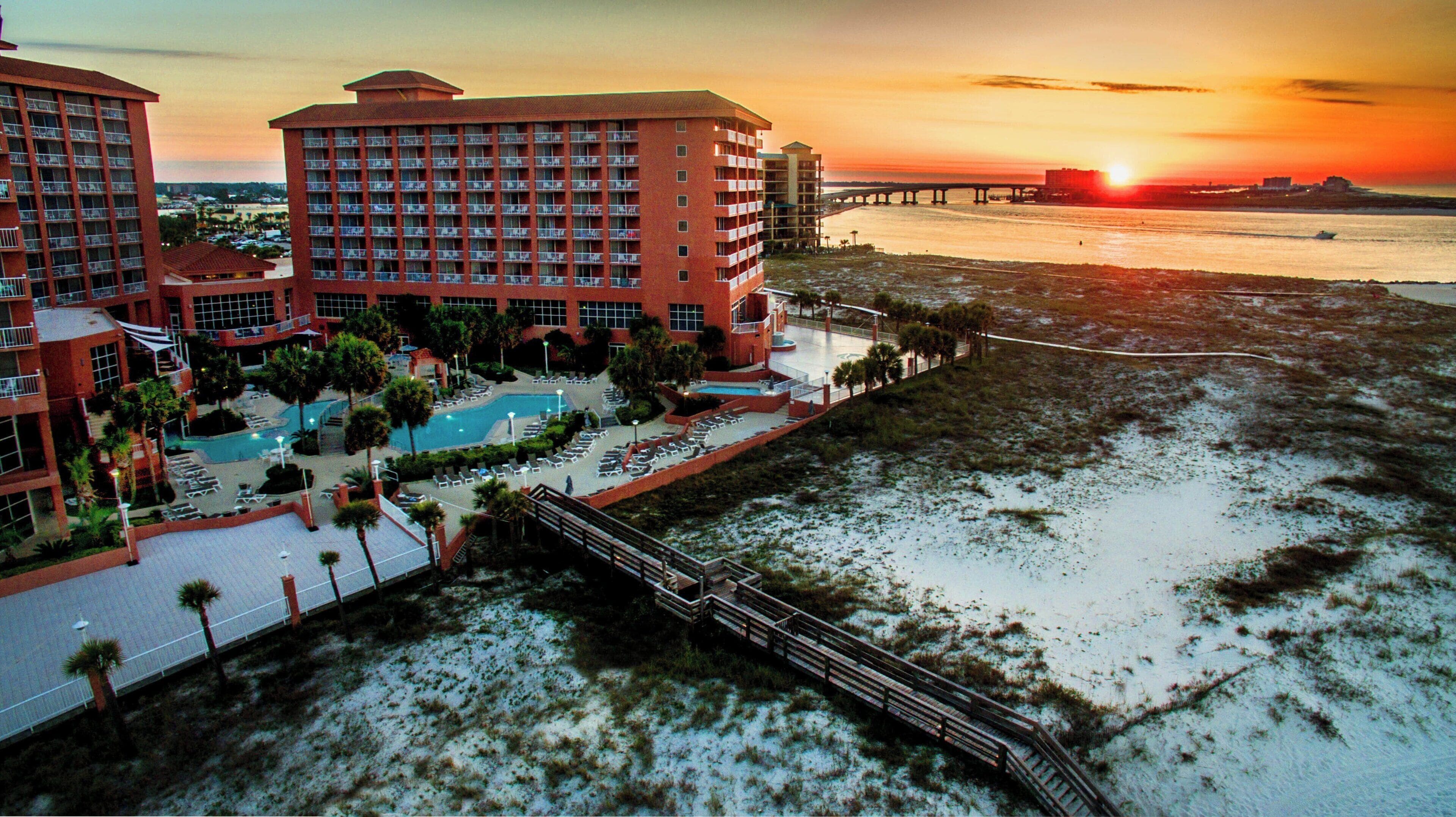 A hotel with multiple floors, a swimming pool, and a beach view.