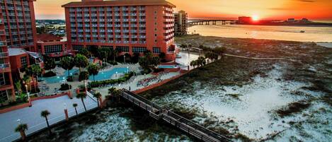 A hotel with multiple floors, a swimming pool, and a beach view.
