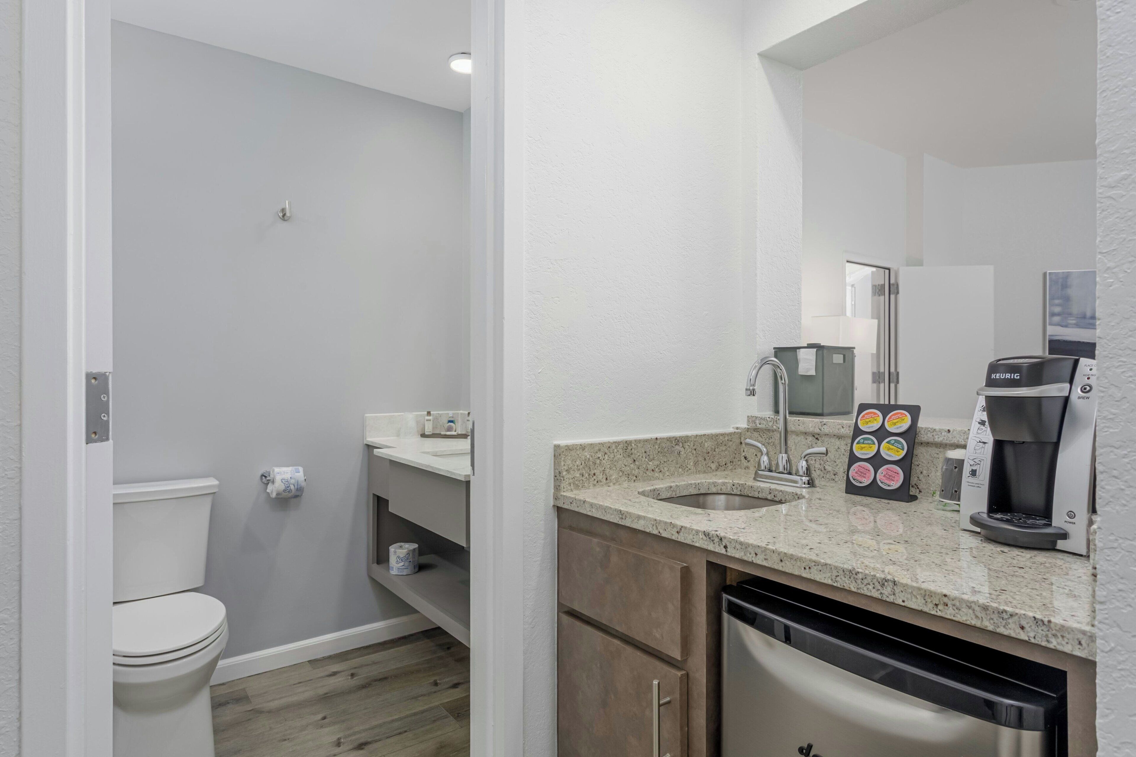 Une salle de bain moderne équipée de toilettes, d’un lavabo et d’une machine à café.