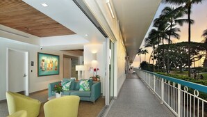 A corridor with a view of palm trees and a railing.