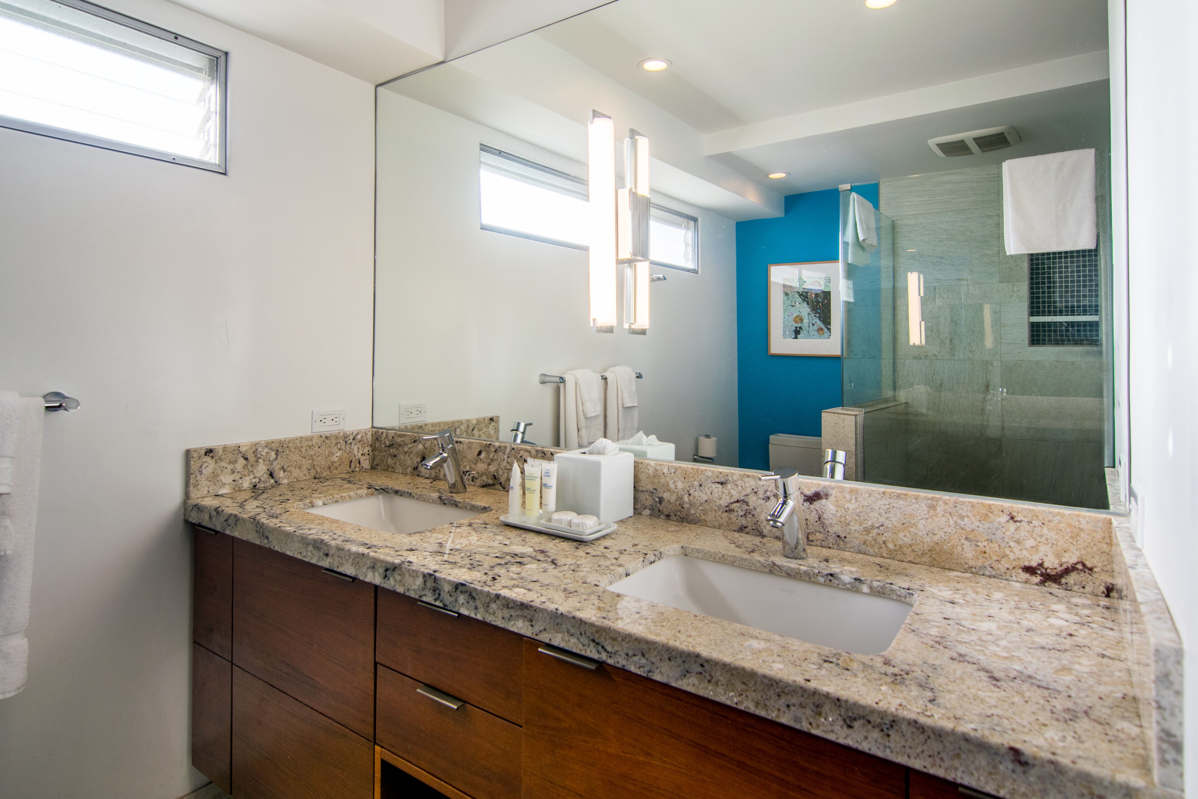 A bathroom with two sinks, a large mirror, and a shower area.