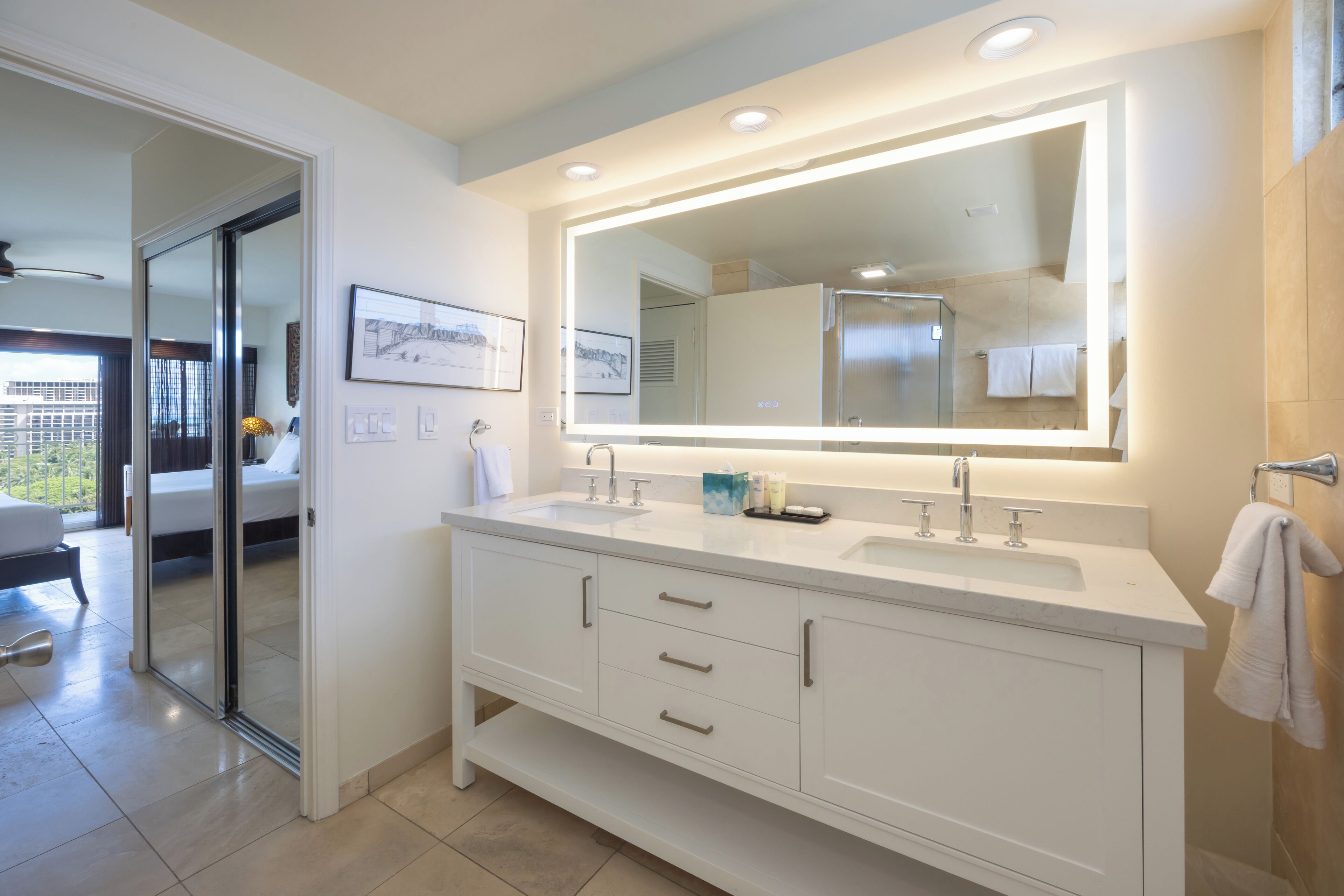 A modern bathroom with a large mirror, two sinks, and a shower.