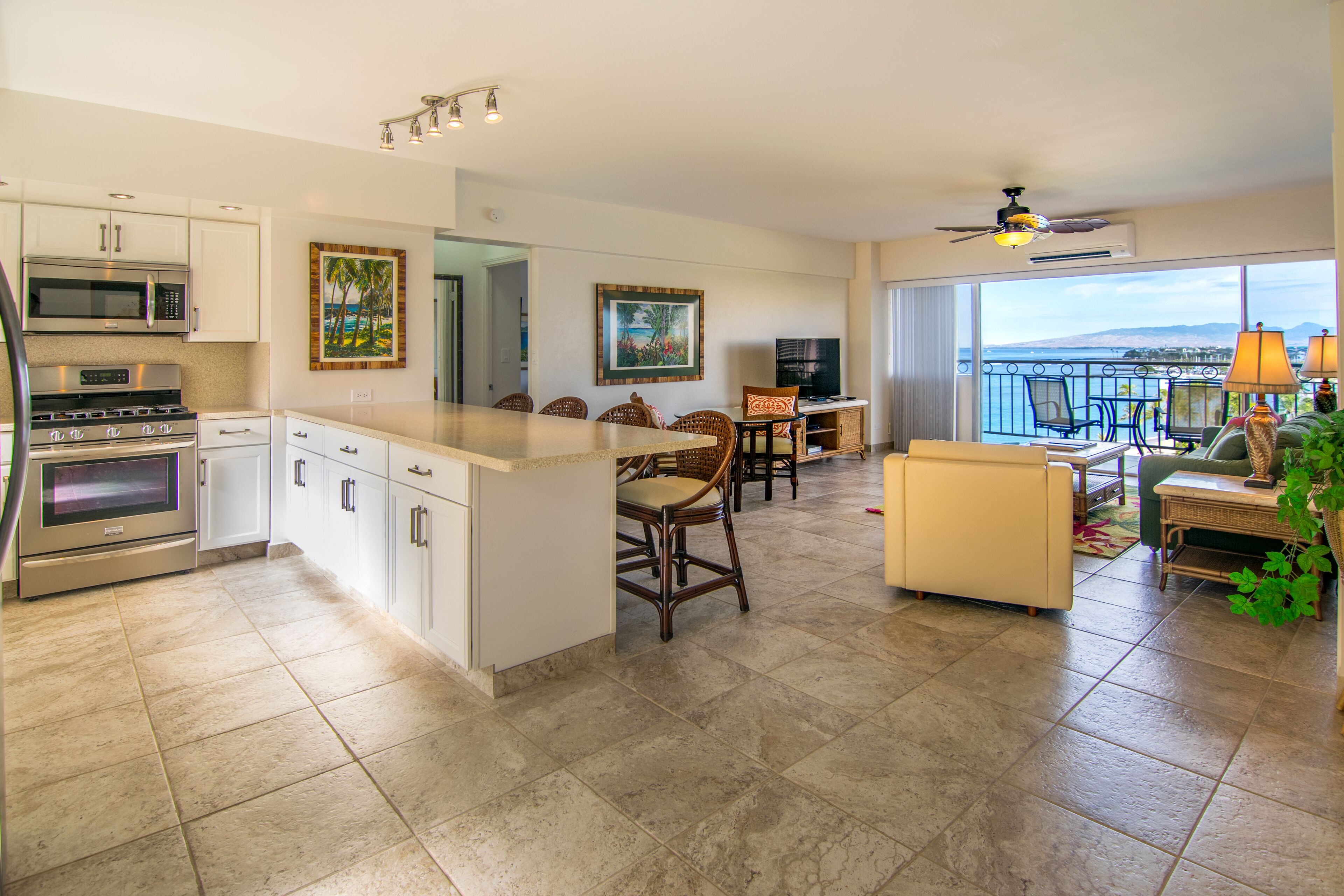 A modern kitchen with white cabinets, a large island, and a dining area with wicker furniture.
