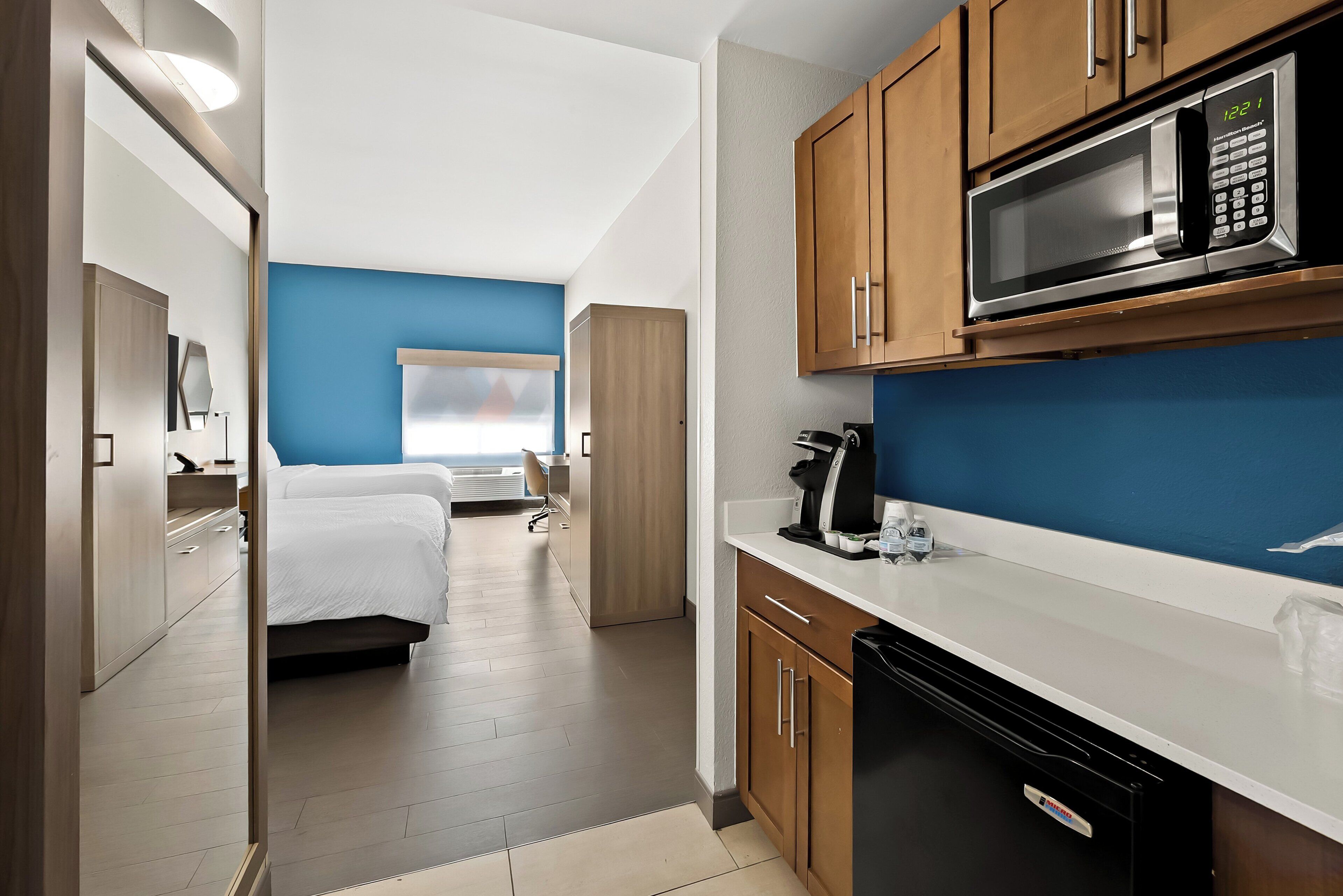 Une chambre d’hôtel moderne équipée d’une kitchenette, d’un lit et d’une salle de bain.