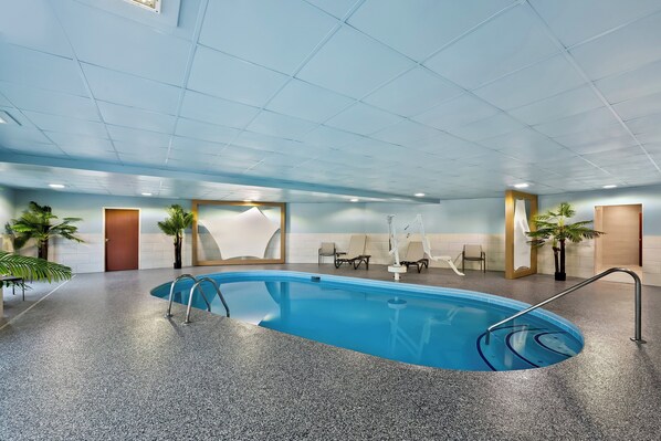 An indoor swimming pool with a granite floor, lounge chairs, and potted plants. - Holiday Inn Express & Suites Raleigh NE - Medical Ctr Area by IHG (Raleigh)